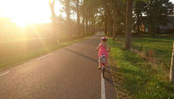 Ein Mädchen fährt auf seinem Fahrrad eine Straße entlang.